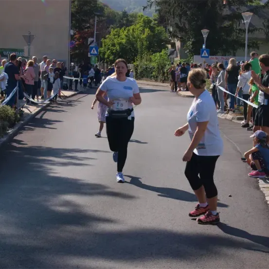 Eine Marathonläuferin mit der Nummer 18 sprintet die Straße hinunter, während Zuschauer an der Seite stehen.