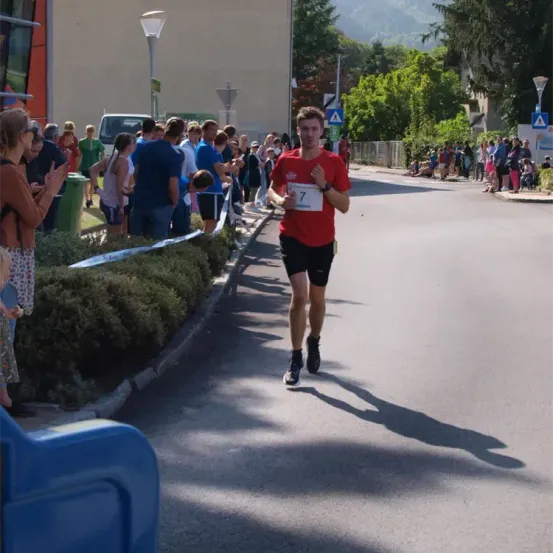 Ein Mann läuft einen Marathon mit der Nummer 7 auf seinem Shirt, mehrere Leute beobachten ihn von der Seite.