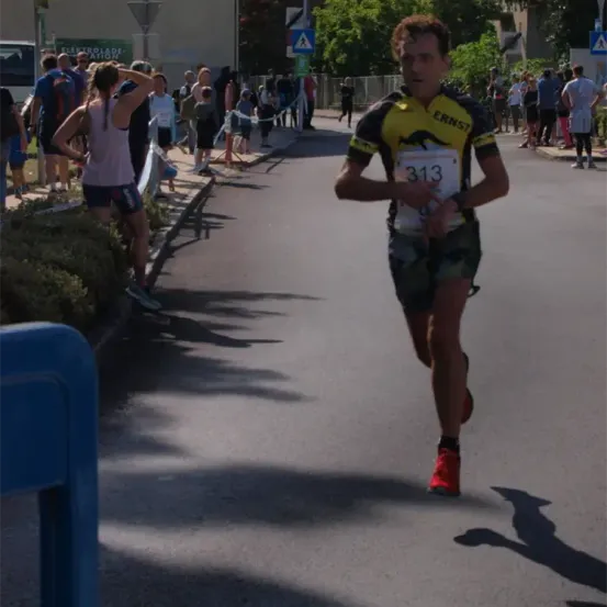 Ein Läufer mit der Nummer 313 nimmt an einem Marathon teil und läuft die Straße hinunter, während Zuschauer an den Seiten stehen.