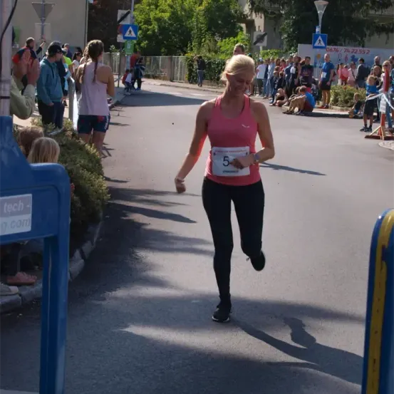 Eine Marathonläuferin mit der Nummer 5 auf ihrem Trikot läuft in der Mitte der Straße, während Zuschauer von der Seite zusehen.