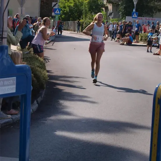 Ein Läufer mit der Nummer 15 läuft in einem Marathon auf einer Straße, wobei eine Menge Zuschauer auf der Seite steht.