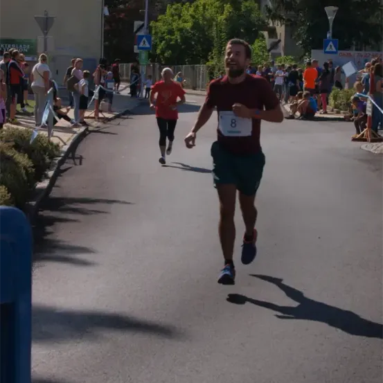 Ein Marathonläufer mit einem Shirt mit der Nummer 8 läuft auf einer Straße, an der eine Menge Menschen steht.
