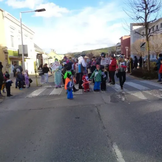 Eine Gruppe von Menschen in bunten Kostümen und mit Schildern unterwegs, wahrscheinlich bei einem Umzug.