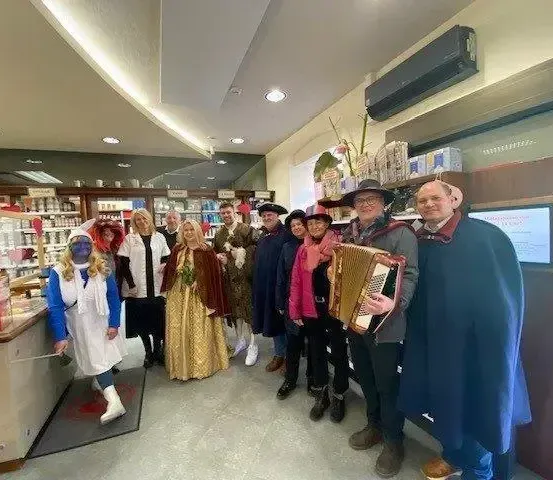 Eine Gruppe von Menschen in Kostümen steht in einem Geschäft, ein Mann spielt Akkordeon.