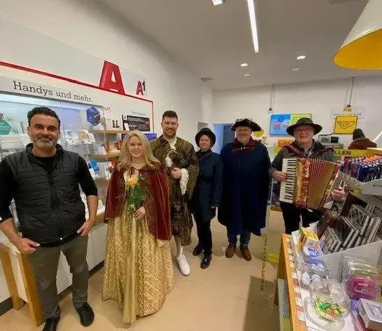 Eine Gruppe von Menschen in Kostümen posiert in einem Geschäft, einer spielt Akkordeon.