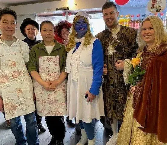 Gruppe von Menschen in Kostümen, einer in einer Krankenschwester-Kleidung, ein anderer mit blauer Gesichtsbemalung und andere in verschiedenen Kostümen, posiert für ein Foto.