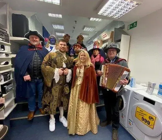 Eine Gruppe von Menschen in Kostümen posiert für ein Foto in einem Raum mit Geräten.