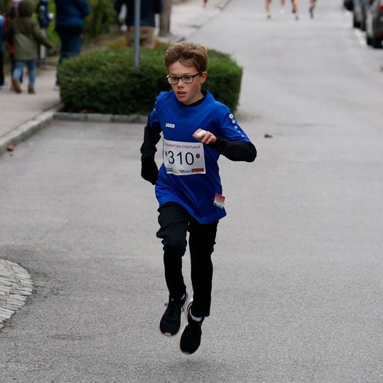 Ein junger Junge mit einem Nummernschild 310 auf seinem Shirt läuft in einem Rennen.