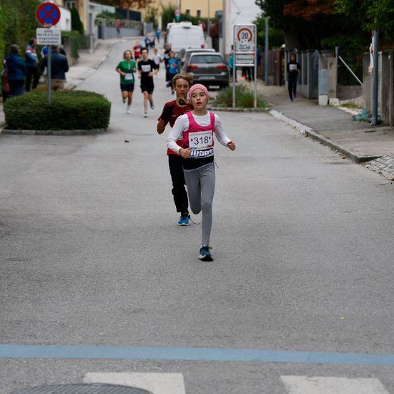 Eine Gruppe von Läufern nimmt an einem Marathon teil. Der Läufer vorne hat die Nummer 318 auf seinem Trikot. Dahinter laufen mehrere Personen.