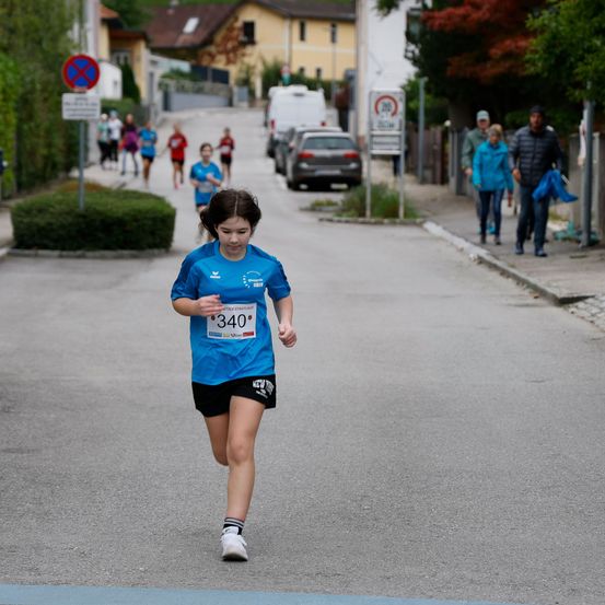 Ein Mädchen läuft einen Marathon mit der Nummer 340 auf ihrem Shirt. Es gibt Leute, die auf dem Bürgersteig gehen.