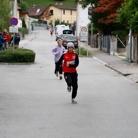 Ein Marathonläufer in rot-schwarzem Outfit läuft eine Straße hinunter, auf deren Trikot die Nummer 80 zu sehen ist.