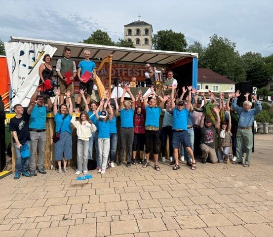 Eine Gruppe von Menschen in blauen T-Shirts posiert für ein Foto vor einem Lastwagen mit Musikinstrumenten.