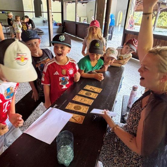 Eine Frau lehrt eine Gruppe von Kindern, wie man Tarotkarten liest, an einem Tisch.