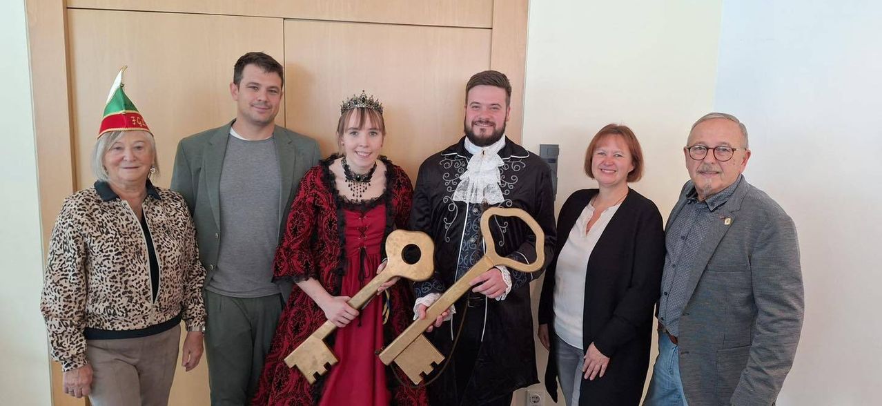 Five individuals are posing for a photograph in a room, two of whom are dressed in costume. They are holding large golden keys, suggesting they might be the key holders of a new building.