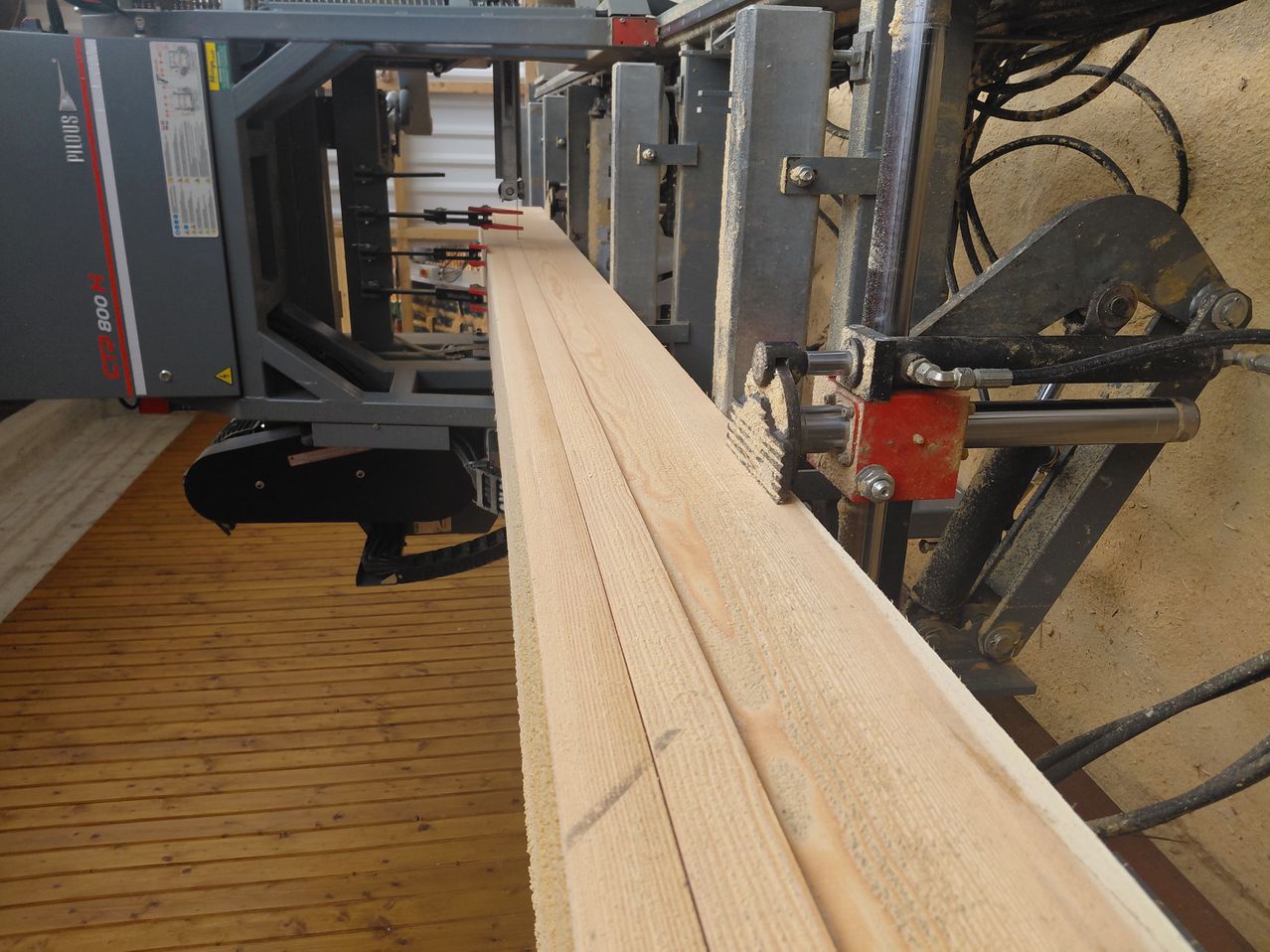 Eine Nahaufnahme eines großen Holzstücks, das in einer Werkstatt von einer Maschine bearbeitet wird.