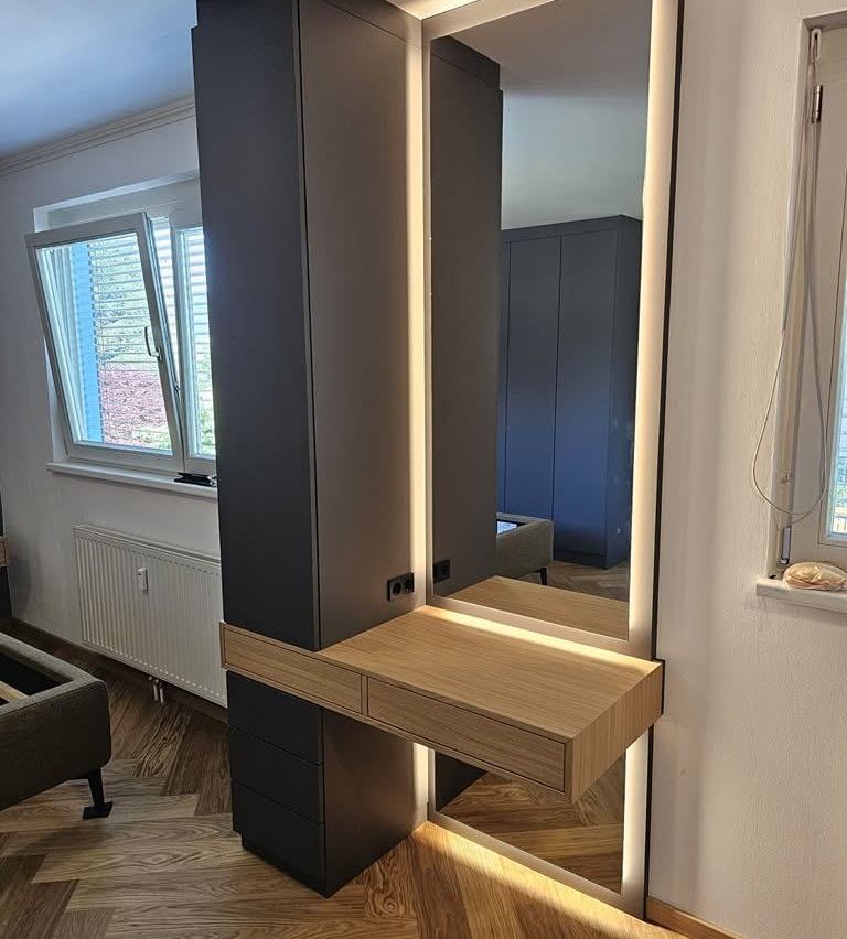 Ein modernes Innendesign mit einem großen Spiegel, einem Holzschreibtisch und einem blauen Kleiderschrank. Der Raum hat einen Holzboden und eine weiße Wand.