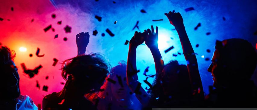 Eine Gruppe von Menschen tanzt in einem Nachtclub mit mehrfarbigen Konfetti.
