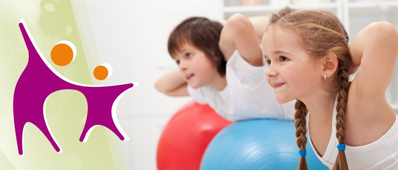 Zwei Kinder spielen auf Gymnastikbällen, einer rot und einer blau, in einem weißen Raum mit einer weißen Wand und Regalen im Hintergrund.