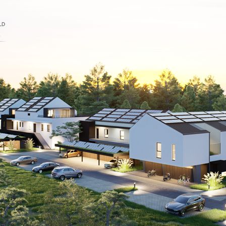 Eine Luftaufnahme einer modernen Wohngegend mit Solarpanelen auf den Dächern der Häuser, vor dem Hintergrund üppiger Bäume. Mehrere Autos sind auf der Einfahrt geparkt.