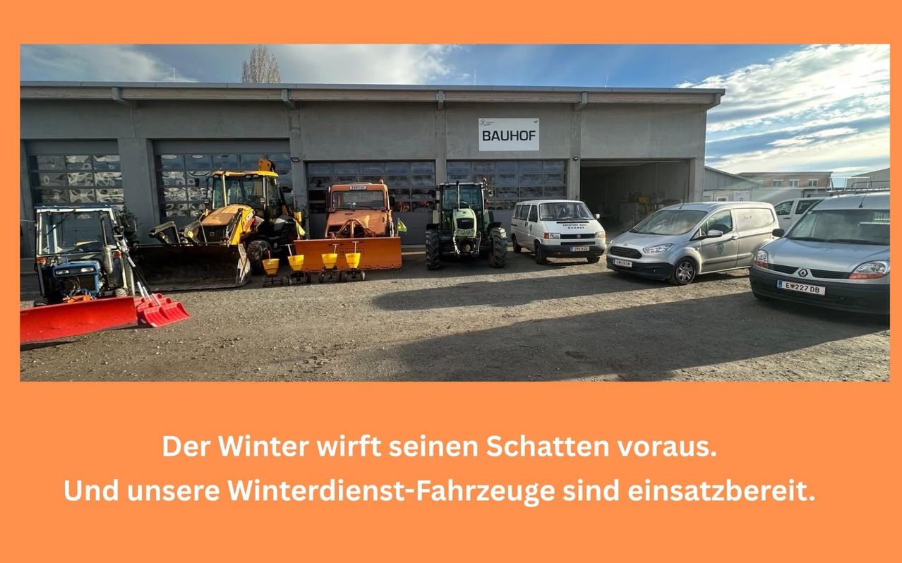 Mehrere Baufahrzeuge sind vor einem Gebäude mit der Aufschrift Bauhof geparkt. Ein Van und ein Auto sind ebenfalls geparkt.