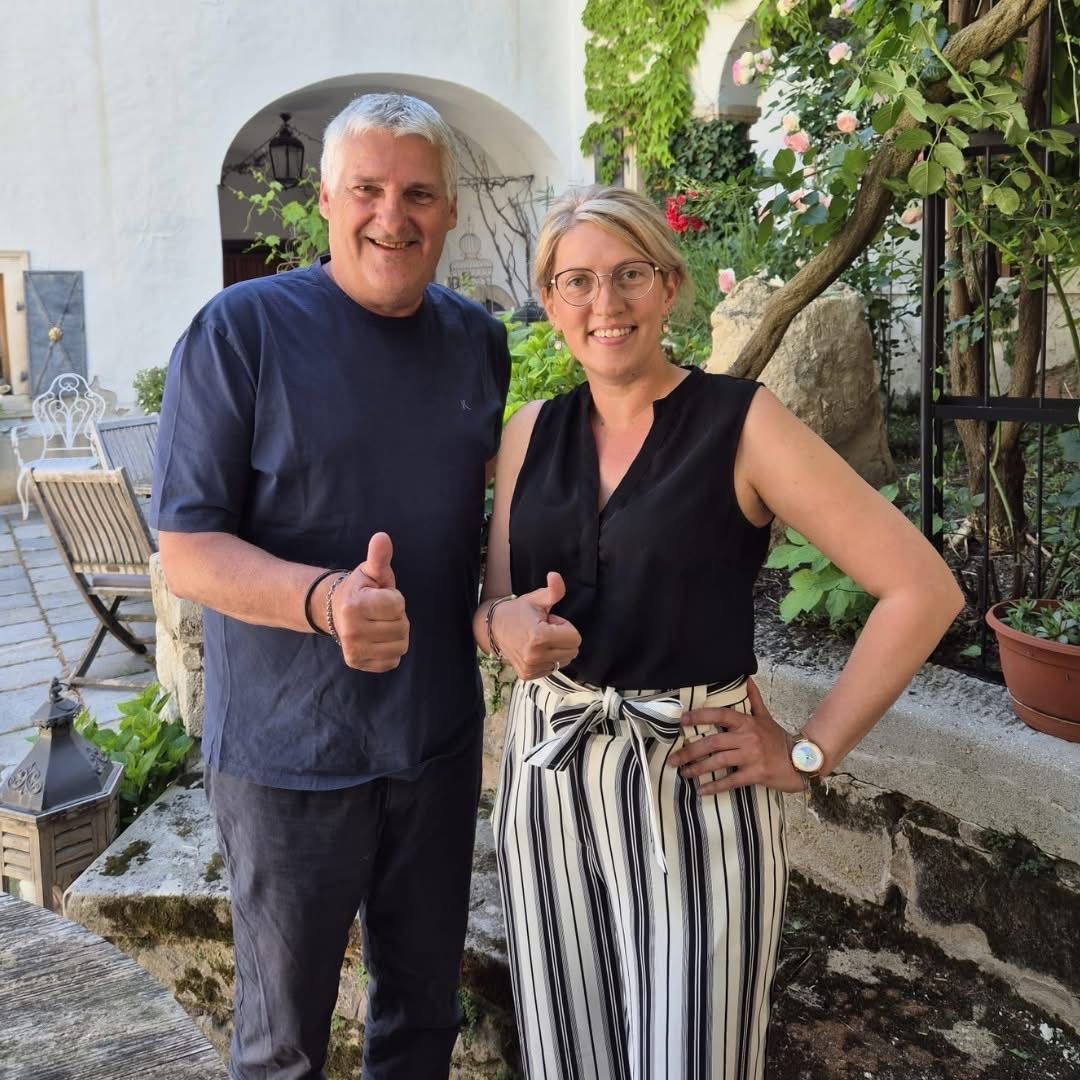 Ein Mann und eine Frau stehen zusammen in einem Garten mit Lächeln im Gesicht und Daumen hoch.