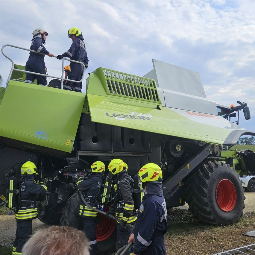 Feuerwehrleute mit Atemschutzgeräten an einem Mähdrescher in Österreich