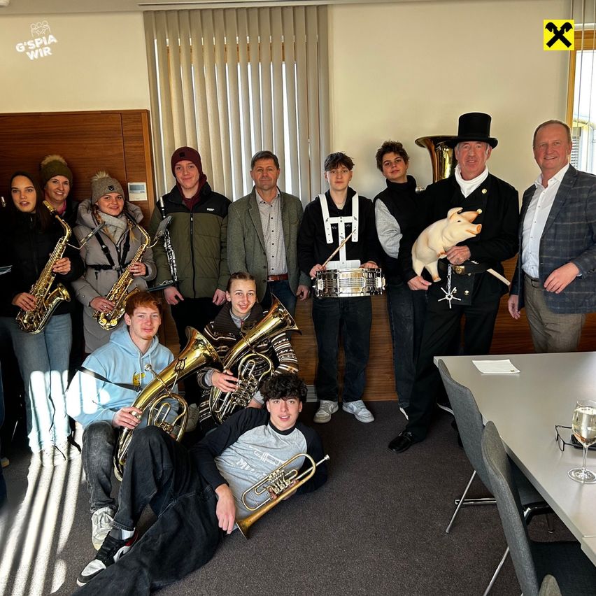 Eine Gruppe von Menschen, wahrscheinlich Musiker, posiert für ein Foto mit ihren Instrumenten. Sie stehen und sitzen um einen Tisch mit einem Weinglas herum.
