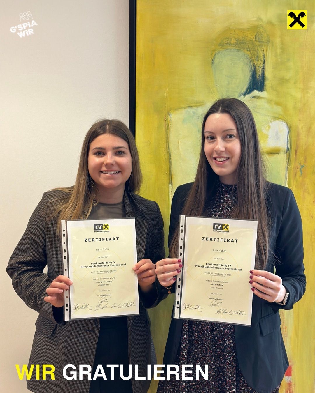 Zwei Frauen stehen und halten Zertifikate. Sie lächeln für ein Foto vor einem gelben Gemälde.