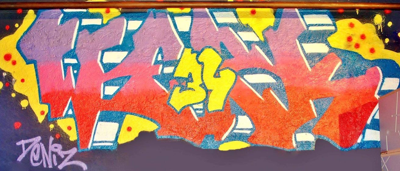 Graffiti-Kunst an einer Wand mit der prominenten Nummer 43 in Gelb, umgeben von abstrakten Formen und Farbspritzern in Rot, Blau und Lila.