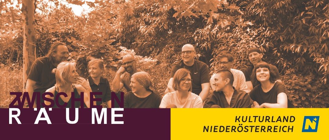 Eine Gruppe von Menschen, sowohl Männer als auch Frauen, lächeln und posieren für ein Foto in einer Waldumgebung. Das Bild hat einen warmen, sepiafarbenen Ton.