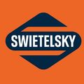 Orange Hintergrund mit einem blauen und weißen Logo, das 'SWIETELSSKY' liest. Das Logo hat ein charakteristisches Design mit einer scharfen, gewinkelten Linie.