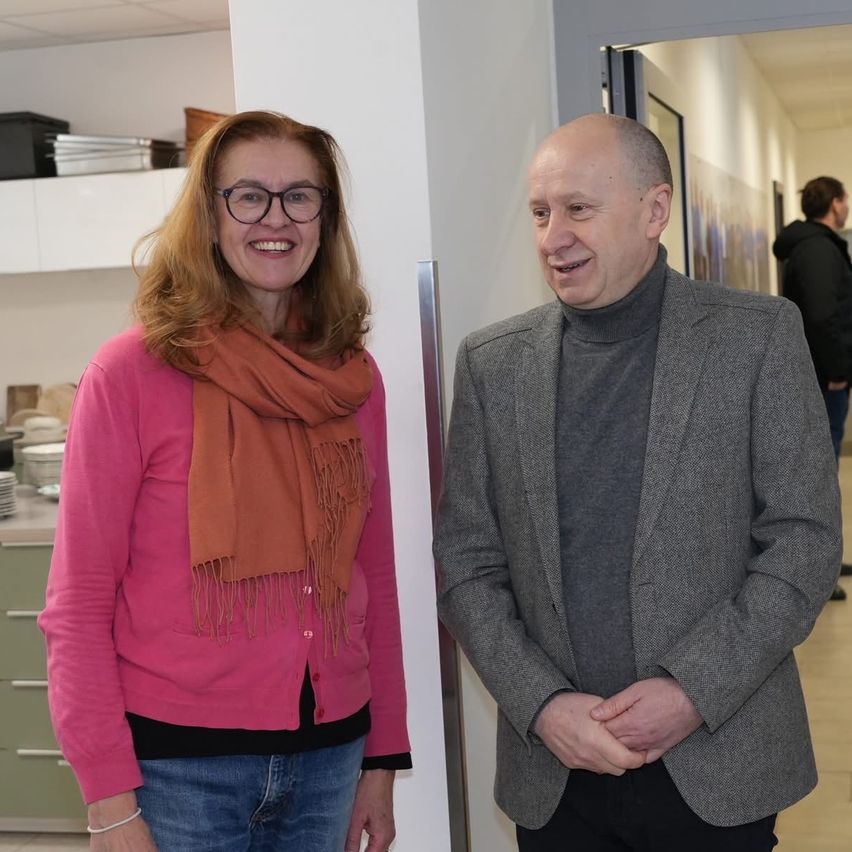 Ein Mann und eine Frau stehen nah beieinander und lächeln in einem Innenbereich.