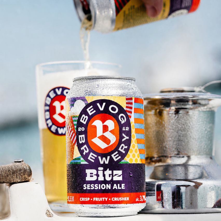 A can of Bitz Session Ale is being poured into a glass on a boat deck, with a lamp and a logo in the background.