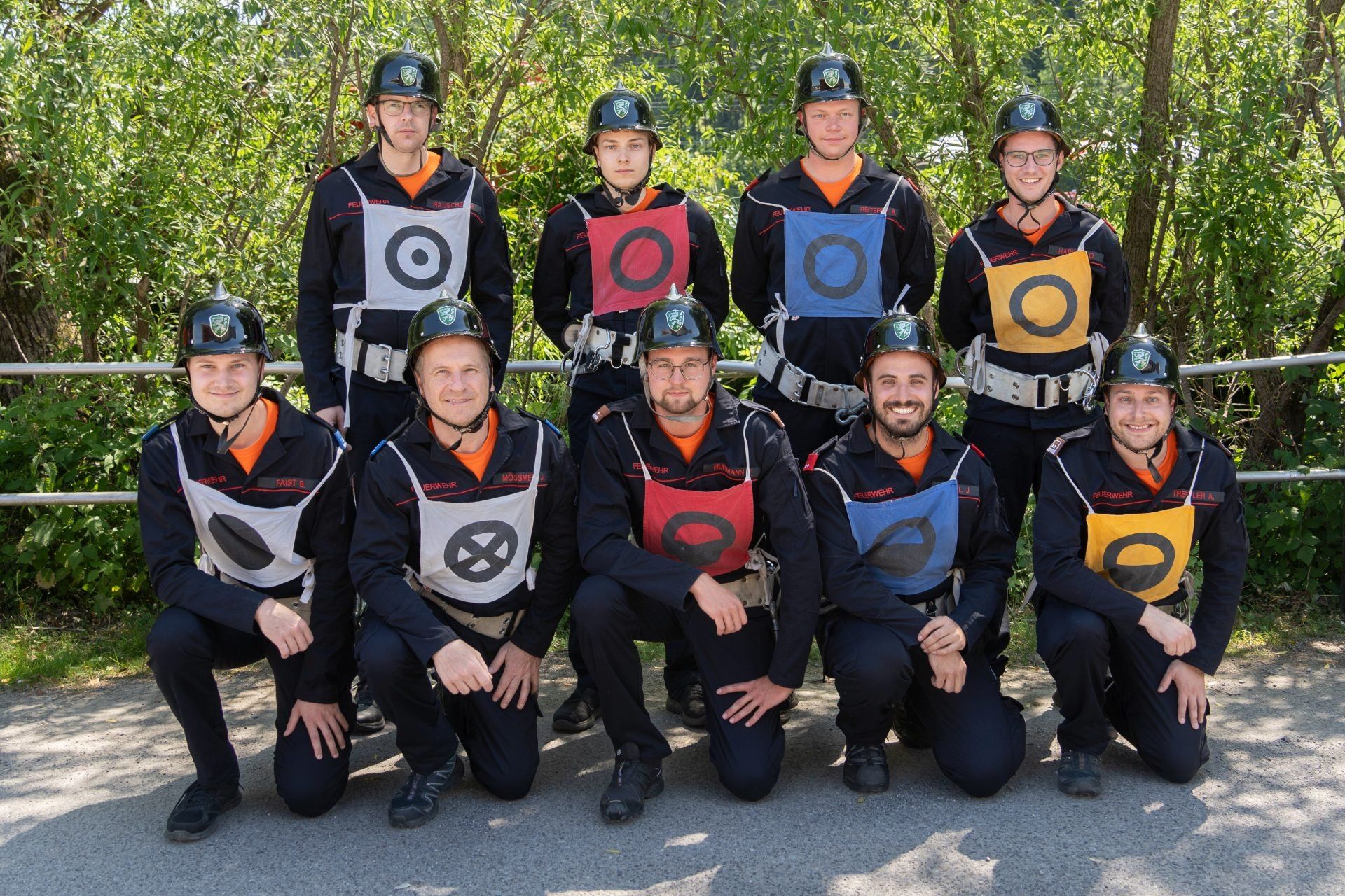 Eine Gruppe von Personen in Uniform und Helmen posiert für ein Foto, einige mit sichtbaren Sicherheitsabzeichen und Flaggen.