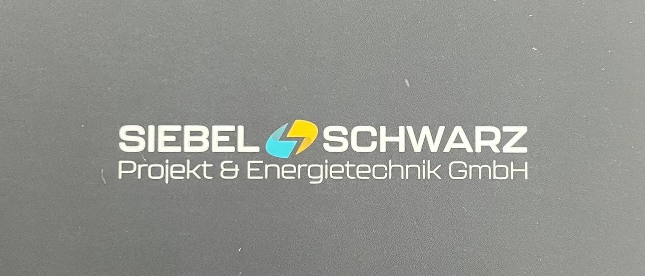Das Logo für SIEBEL SCHWARZ Projekt & Energietechnik GmbH wird auf einem grauen Hintergrund angezeigt. Das Logo zeigt weißen Text mit einem blauen und gelben Blitz-Symbol.