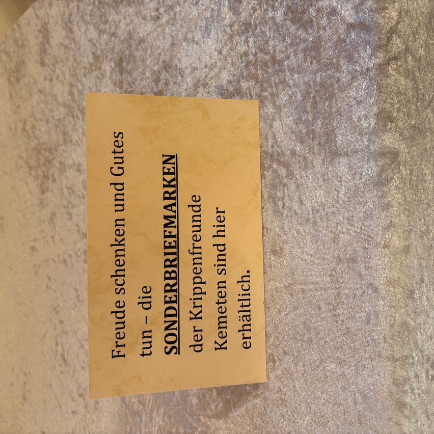 Ein gelbes Papier mit schwarzem Text lautet 'SONDERBRIEFMARKEN' und 'Freude schenken und Gutes tun die - der Krippenfreunde der Kemetlichen erhaltlich sind hier.' Es scheint eine Mitteilung für spezielle Briefmarken zu sein.