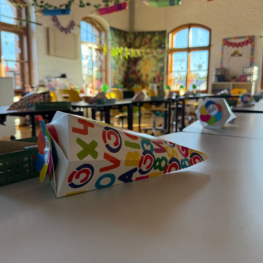Ein Klassenzimmer mit bunten Dekorationen und einem Tisch mit einem kegelförmigen Objekt mit Zahlen und Buchstaben darauf.
