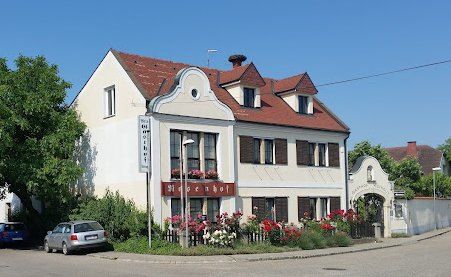 Ein weißes Gebäude mit rotem Dach und Blumenkästen. Ein Auto vor dem Gebäude geparkt.