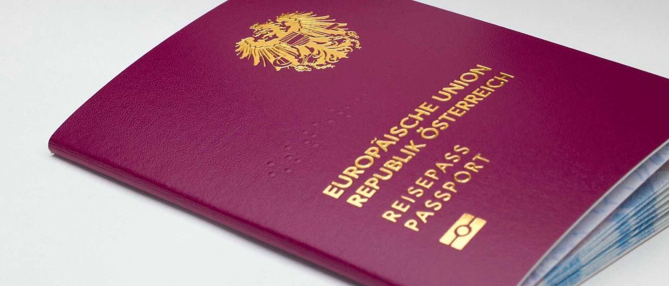 Ein burgunderroter Reisepass mit goldenem Text, der das Wappen der Europaischen Union und den Landesnamen Republik Osterreich zeigt.