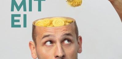 Ein Mann mit einer Schüssel Spaghetti auf dem Kopf und einer Gabel in der Hand, umgeben von medizinischen Werkzeugen auf einem blauen Tuch.