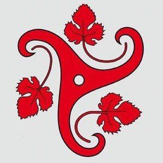 Ein rotes Symbol mit einem kreisförmigen Design in der Mitte und drei blattartigen Strukturen, die sich davon erstrecken. Jedes Blatt hat eine spitze Spitze und einen welligen Umriss. Die Blätter sind in einer dreieckigen Form angeordnet. Das Symbol befindet sich auf einem grauen Hintergrund.