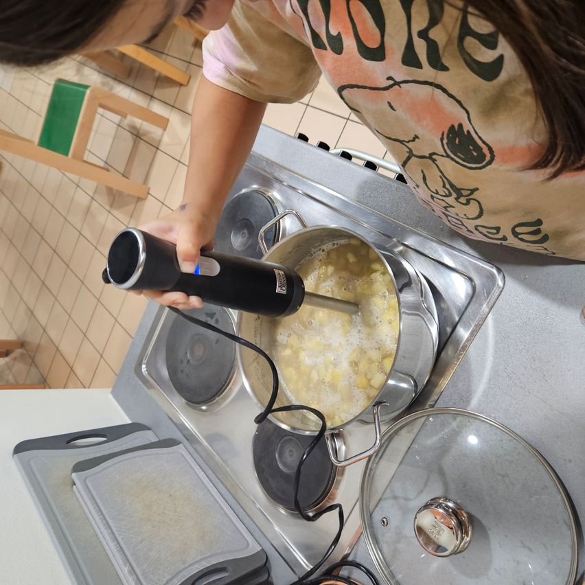 Bild enthält, Person, Cooking, Head, Face, Mashing Food, Food, Stirring Food, Footwear, Shoe, Blow Dryer