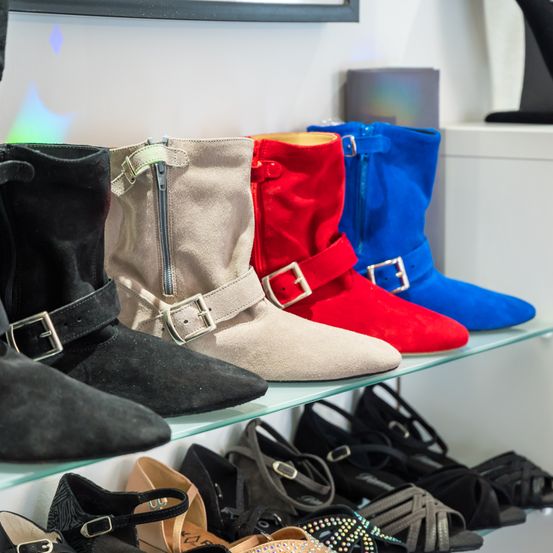 Eine Auswahl an Stiefeln und Schuhen, darunter schwarze, beige, rote und blaue Stiefel mit Reißverschlüssen und Schnallen.