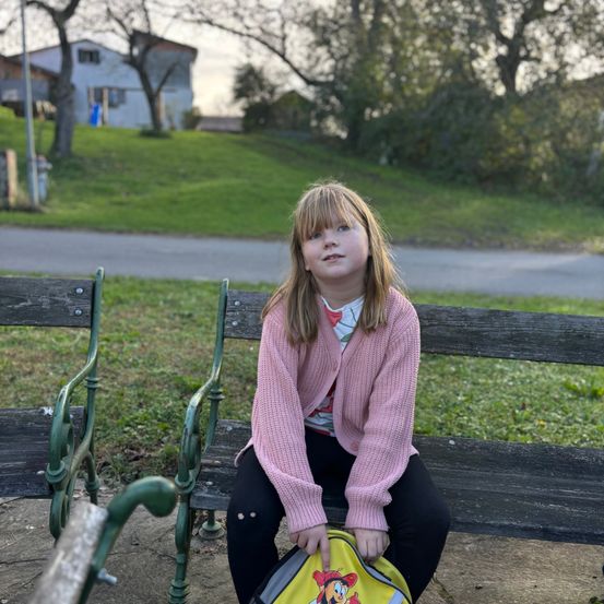 Bild enthält, Person, Sitting, Handbag, Grass, Purse, Bench, Face, Portrait, Sweater, Jeans