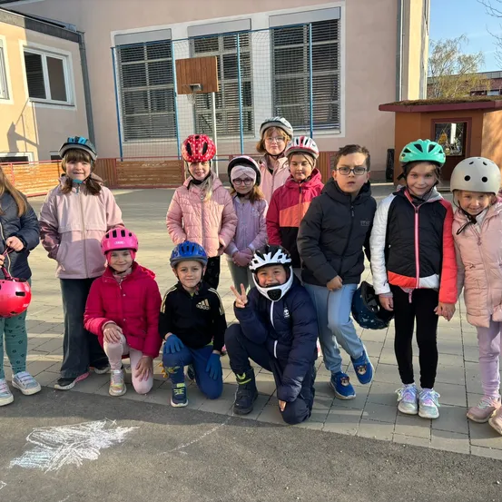 Eine Gruppe von Kindern in Winterkleidung und Helmen posiert für ein Foto vor einem Gebäude. Ein Kreidezeichnung ist auf dem Boden.