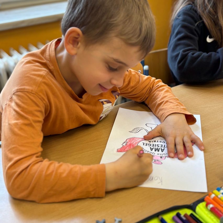 Ein Junge, der ein Bild eines rosa Einhorns mit den Worten 'Ich bin ein Einhorn' darauf ausmalt.
