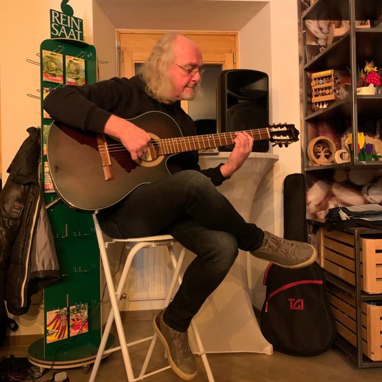 Bild enthält, Guitar, Musical Instrument, Adult, Male, Man, Person, Guitarist, Shoe, Face, Furniture