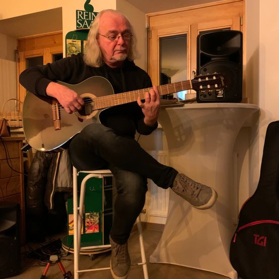 Bild enthält, Guitar, Musical Instrument, Adult, Male, Man, Person, Shoe, Guitarist, Face, Furniture