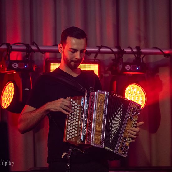 Bild enthält, Adult, Male, Man, Person, Lighting, Musical Instrument, Face, Head, Accordion