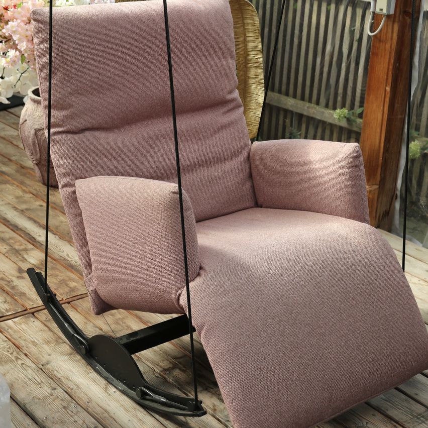 Ein rosa Sessel auf einer Holzterrasse mit einem Metallschaukel befestigt. Der Stuhl ist gepolstert und scheint bequem.